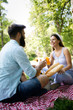 © NDABCREATIVITY - Happy young couple enjoying picnic in park.