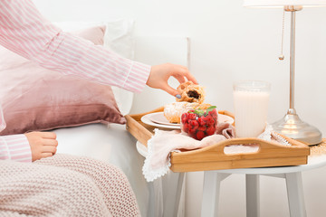 Wall Mural - Young woman having tasty breakfast in bed