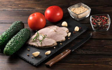 .baked meat with cucumbers and tomatoes on a wooden background