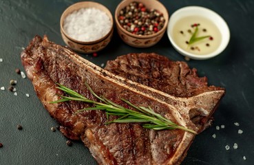 Grilled T-bone steak on a stone table. With rosemary and spices. 