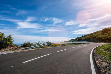 Empty long mountain road to the horizon on a sunny summer day at bright sunset