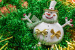 © Анна Чернецова - Background in the form of Christmas tree decorations - a cheerful snowman, green and golden rain, side view