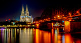 Fototapeta Paryż - Night View of Cologne Cathedral (Kolner Dom) and Rhine river under the Hohenzollern Bridge, Cologne city skyline at night, North Rhine Westphalia region, Germany.