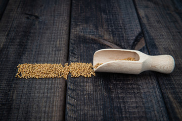 Wall Mural - Mustard with a scoop on a dark wooden countertop. The concept of eating and adding spices to dishes. Improving the taste of dishes, sharp expressive taste.