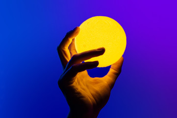 Man holding yellow moon shape illuminated sphere