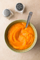 Wall Mural - Fresh homemade pumpkin puree in bowl with spoon, salt and pepper on the side, photographed overhead (Selective Focus, Focus on the dish)