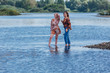 © Smile - Two pretty sisters standing in river next to the shore on a cloudy windy summer day, having fun and laughing.