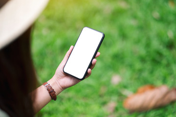 mockup image of a woman holding black mobile phone with blank desktop screen in the park