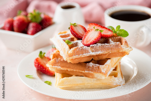 Fotografía Belgian waffles with strawberry and powdered sugar on white plate, pink backgrou