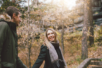 Happy young couple in love friends dressed in casual style walking together on nature park forest in cold season, family advenure travel