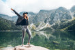 happy woman hands up looking at lake in mountains