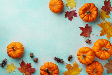 Wall Mural - Autumn Thanksgiving background. Pumpkins and maple leaves on turquoise table top view.