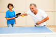© caftor - Happy mature man and woman playing table tennis