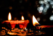 Deepawali Concept. Low Light Photo Of Two Blurred Earthen Lamps With One Lamp In The Foreground And Some Coins On The Floor