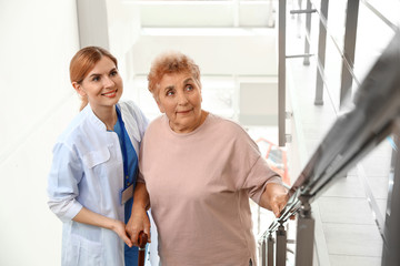 Canvas Print - Nurse assisting elderly woman on stairs indoors