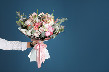man holding beautiful flower bouquet on blue background, closeup view. space for text