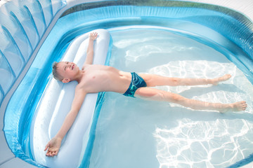 the boy lies relaxed in the pool