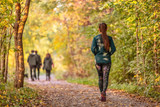 Fototapeta  - Woman walking in autumn forest nature path walk on trail woods background. Happy girl relaxing on active outdoor activity.