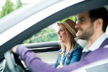 Wall Mural - Happy young couple sitting in car, talking.