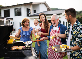 Portrait of multigeneration family outdoors on garden barbecue, grilling.