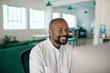 © mavoimages - Smiling African American businessman using a computer in an office