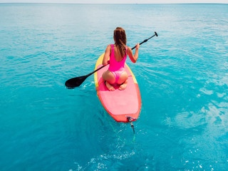 Wall Mural - Attractive woman on stand up paddle board on a quiet blue ocean. Sup surfing in sea
