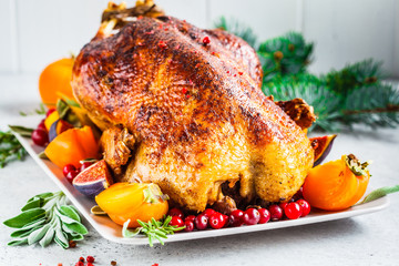 Christmas baked duck with herbs and fruits on gray plate, white background.