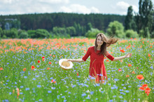 Lovely Young Romantic Woman In Straw Hat On Poppy Flower Field Posing On Background Summer. Wearing Straw Hat. Soft Colors
