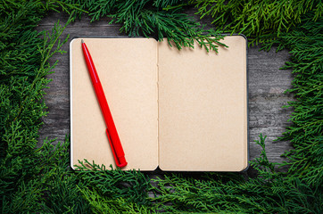 Wall Mural - Christmas frame from fir branches on a background of an old gray board around an open notebook with blank sheets. Frame of fir branches. Christmas card blank concept.