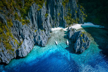 El Nido, Palawan, Philippines. Aerial Above View Of Secret Hidden Rocky Lagoon Beach With Tourist Banca Boats In The Cove Surrounded By Karst Scenery