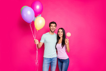 Photo of funny guy and lady holding air balloons in hands came to parents birthday party with sugar bonbon wear casual outfit isolated pink color background