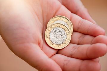 Kid hand showing money two pound coins on his hands,Child holding new British one pound on both hands, New pound coin, 2017 design