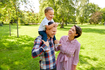 family, leisure and people concept - happy mother, father and little son having fun at summer park