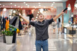 Happy young man posing holding a large number of packages with shopping in a raised hand, in the other hand a telephone expressing an emotion of complete happiness and joy. Pleasure from shopping.  