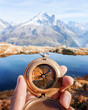 Man with compass in hand in high mountains near clear lake. Travel concept. Landscape photography