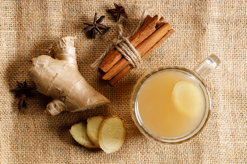 Wall Mural - Ginger tea in a glass with fresh sliced ginger and cinnamon