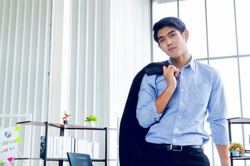 Young Asian Businessperson is standing smart poses and smile at co working space decorated in modern office style for startup business students and freelancers