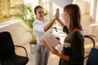 © JustLife - Two young colleagues giving each other a high five