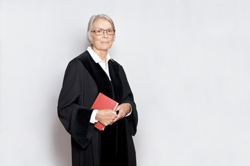 Female jurisdiction concept: friendly german judge in a black judge's gown holding a book with the constitutional text.