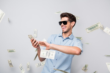 Photo of cheerful excited ecstatic overjoyed man throwing money away showing his wealthiness wearing denim isolated over grey color background