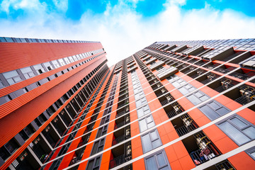 high building apartment with cloud blue sky, look up view, red building. red condominium. Very tall condominium from below. Blue sky full of cloud