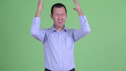 Wall Mural - Studio shot of stressed Asian businessman getting bad news