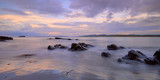 Fototapeta Krajobraz - Mauve Sunset with wispy clouds on Pollan Beach, Inishowen, Ireland.  Featuring rocks algues and sand with viiew of Malin Peninsula on horizon