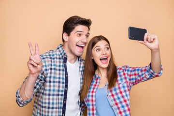 Sticker - Close-up portrait of his he her she nice attractive lovely funky cheerful cheery couple wearing checked shirt taking selfie showing v-sign isolated over beige pastel color background