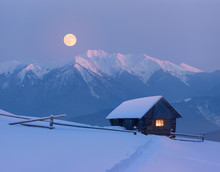 Christmas Landscape With A Snowy House In The Mountains On A Moonlit Night