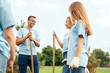 © Viktoriia - Volunteering. Young people volunteers outdoors planting trees talking looking at each other happy close-up