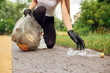 © Viktoriia - Plogging. Young girl volunteer in gloves running outdoors picking up litter plastic bottle close-up