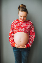 Young Pregnant Woman Standing And Looking At Her Belly