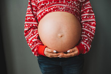 Pregnant Caucasian Woman Wearing Red Sweater With Bare Belly Close Up