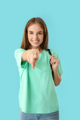 Poster - Beautiful female student pointing at viewer on color background